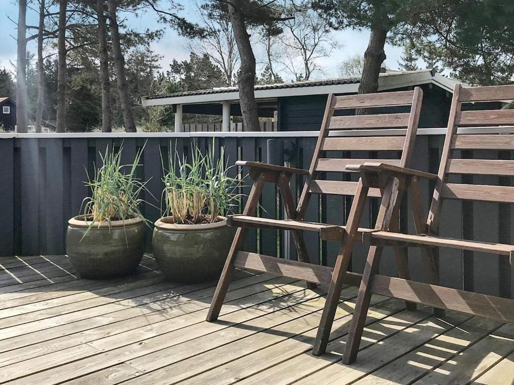 布拉万德Three-Bedroom Holiday home in Blåvand 21的甲板上的木椅和盆栽植物