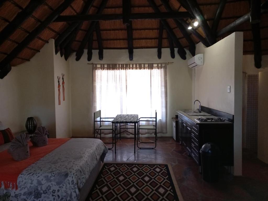 奥马鲁鲁罗迪娜野生山林小屋的一间卧室配有一张床、一张桌子和一个窗户。