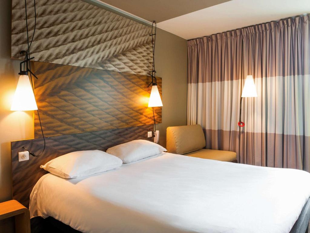 库尔布瓦宜必思巴黎拉德芳斯库尔布瓦酒店的酒店客房带一张大床和一把椅子