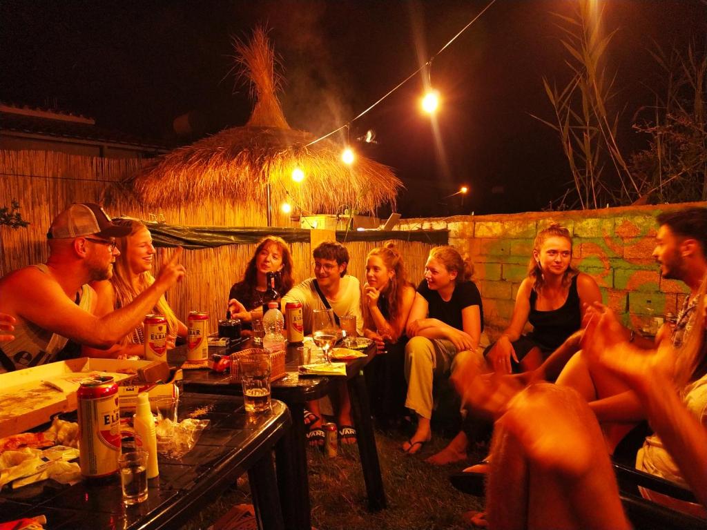 伏罗拉Pinegroove Hostel Vlora的一群人晚上坐在桌子旁