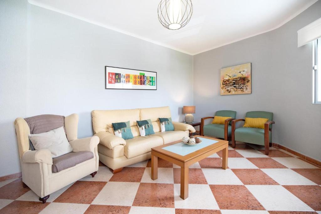 加的斯Descanso en Cádiz的客厅配有两把椅子、一张沙发和一张桌子