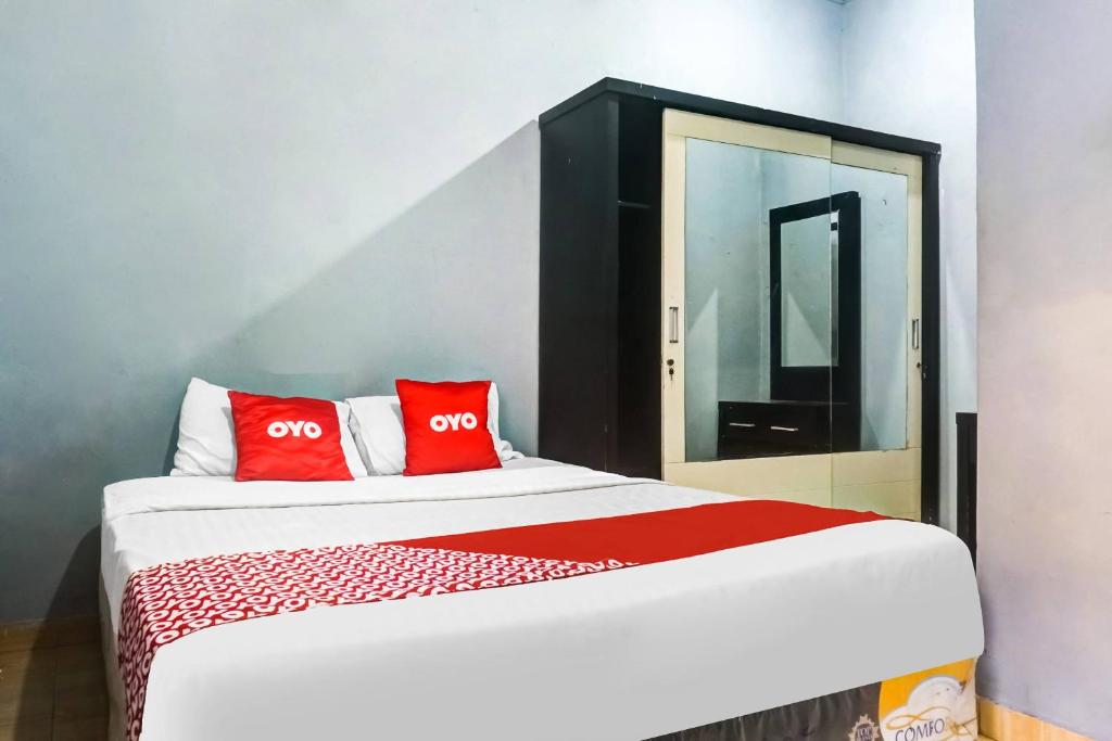 雅加达Super OYO 91259' 59 Residence的一间卧室配有一张带红色枕头的大床
