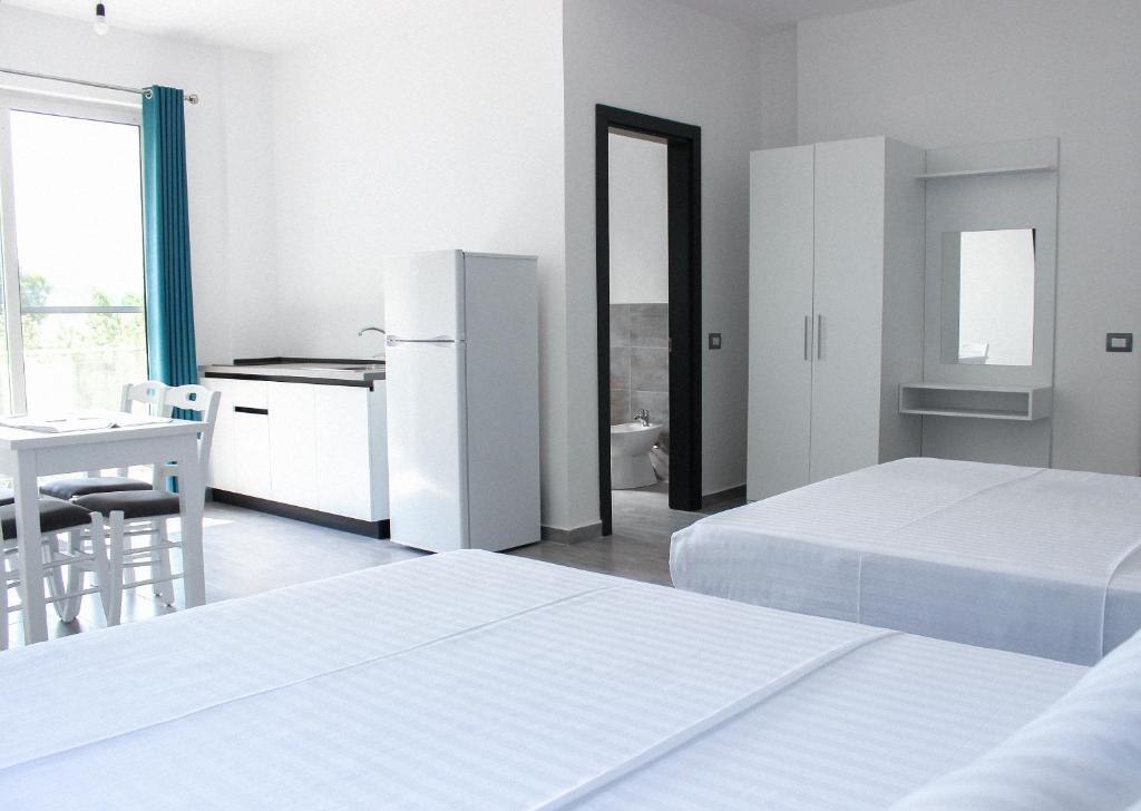 莱什LUMNIK - Hotel & Apartments的一间白色卧室,配有两张床和一台冰箱