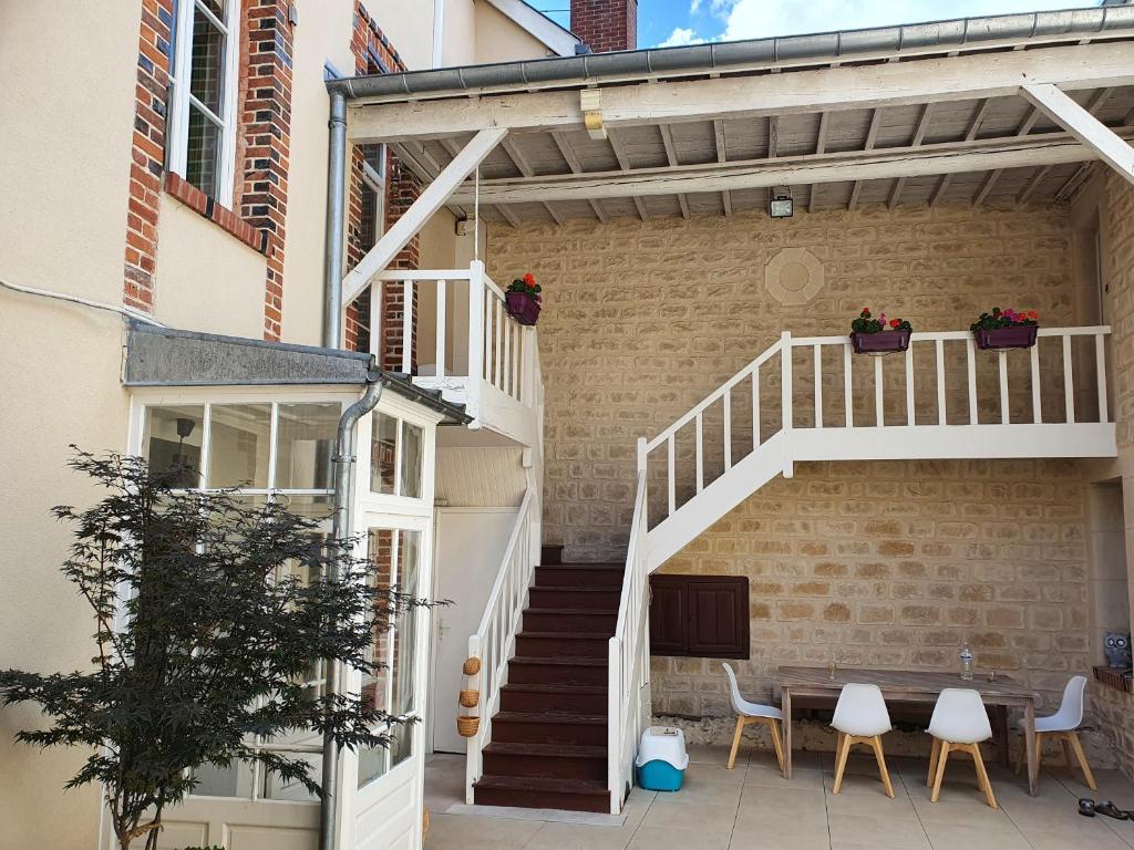 Mareuil-sur-AyLa Cour des Marotiers的一个带楼梯和桌椅的庭院
