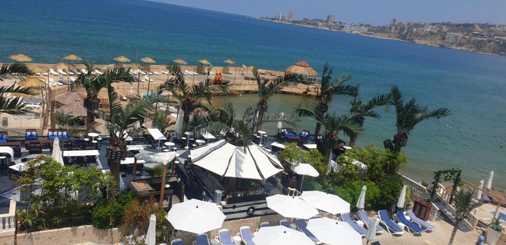 朱尼耶Lamedina Hotel & Resort的享有海滩的空中景致,配有椅子和遮阳伞