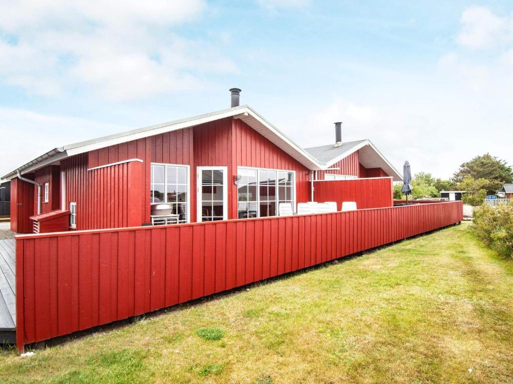 Nørre LyngvigThree-Bedroom Holiday home in Hvide Sande 2的红色的房子,有红色的栅栏