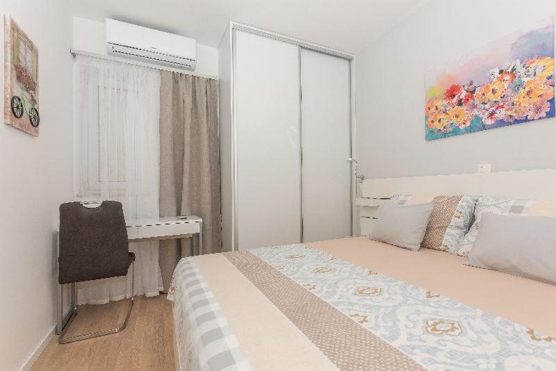马卡尔斯卡Apartment J&J的一间卧室配有一张床、一张书桌和一个窗户。