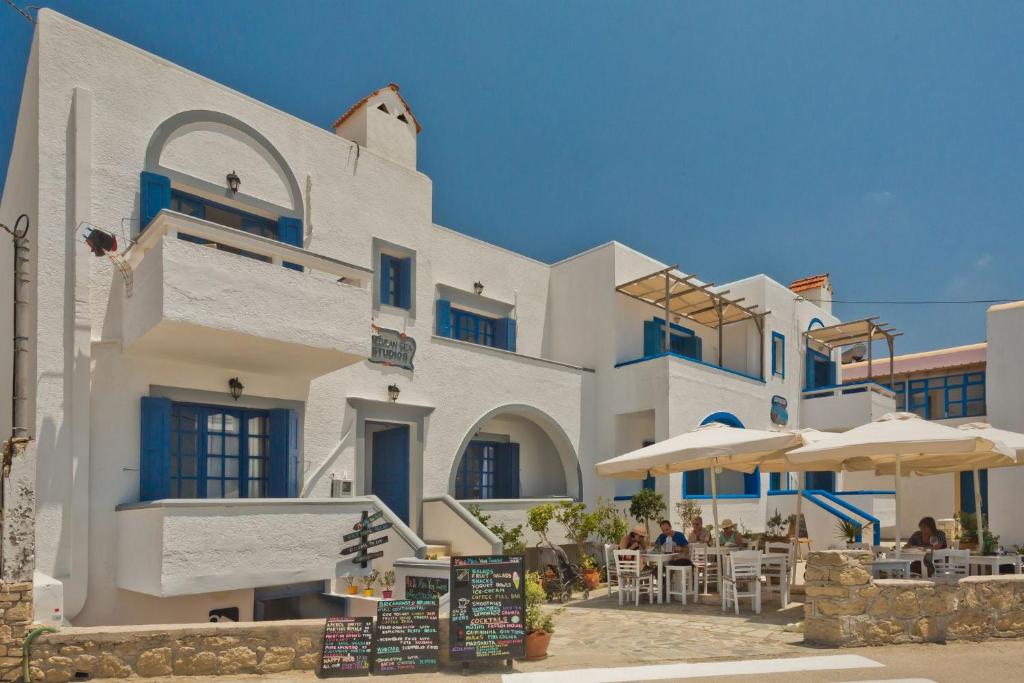 雷夫科斯卡尔帕索爱琴海公寓的一座带桌子和遮阳伞的大型白色建筑