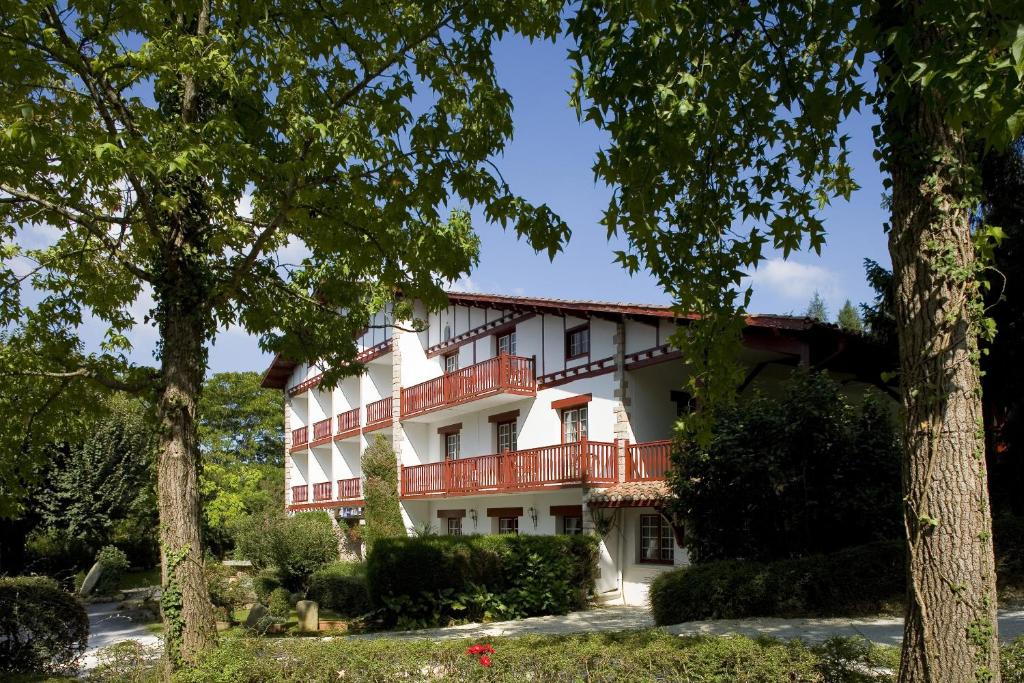 阿伊诺阿Hotel Argi Eder的一座白色的大建筑,设有红色的阳台和树木