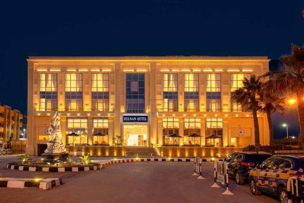 亚历山大Helnan Mamoura Hotel & Events Center的一座大型建筑,前面有汽车停放