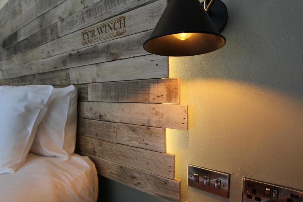 卡迪夫Tyr Winch的一间卧室设有木墙、一张床和一盏灯