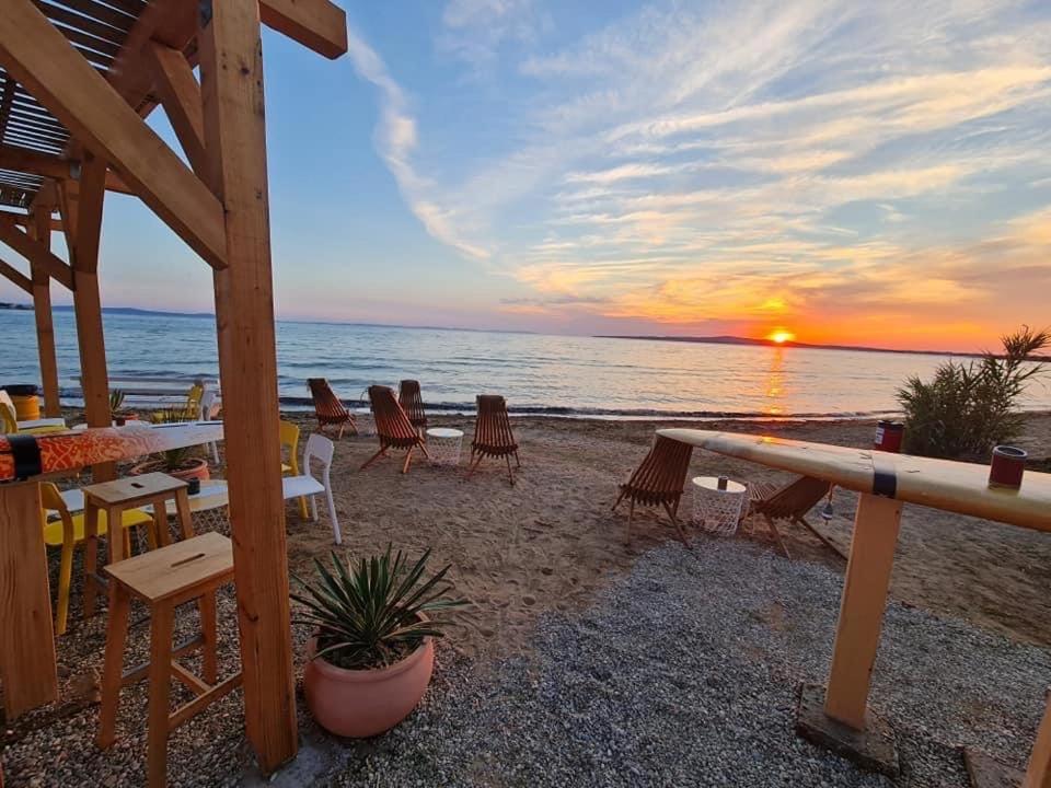 普利拉卡Apartments Lolo的海滩上的日落美景,配有桌椅