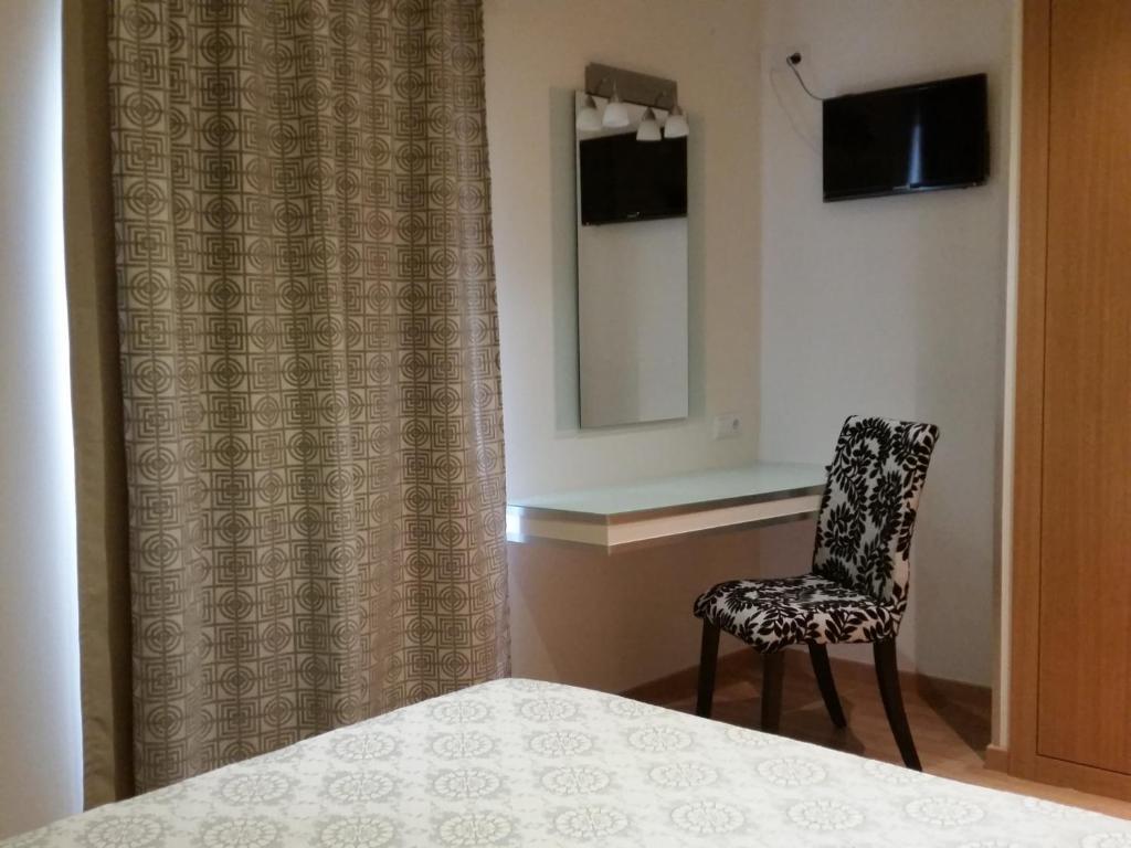 库里亚盘扫洛伦索酒店的一间卧室配有椅子、镜子和一张床