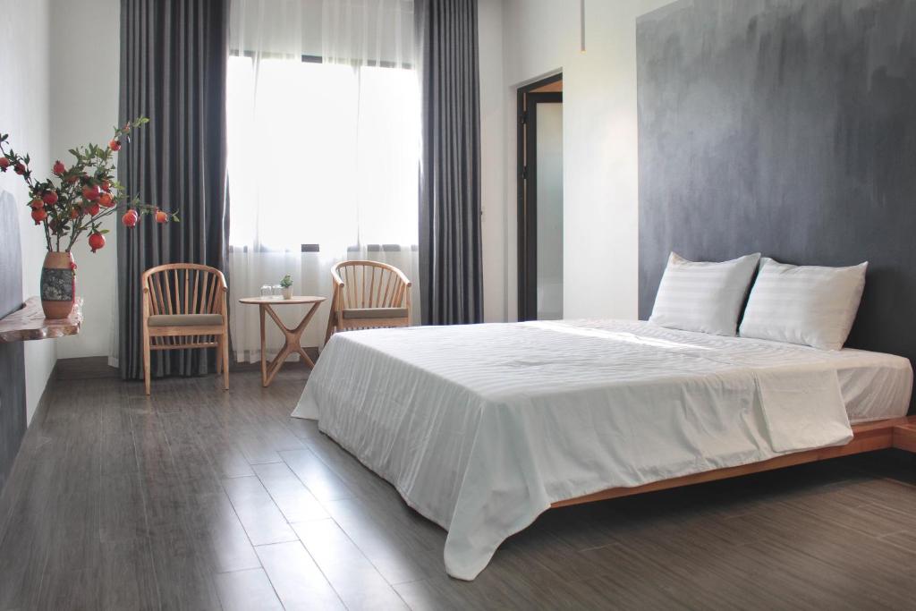 宁平ᴄᴏᴄᴏᴏɴ ʜᴏᴍᴇsᴛᴀʏ ᴛᴀᴍ ᴄốᴄ的卧室配有一张白色的大床和一张桌子