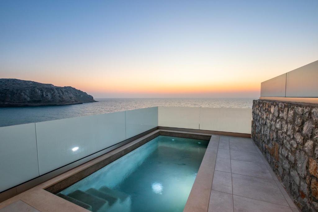 卡尔帕索斯Thalasidi Luxury Suites的一座背景海洋的游泳池