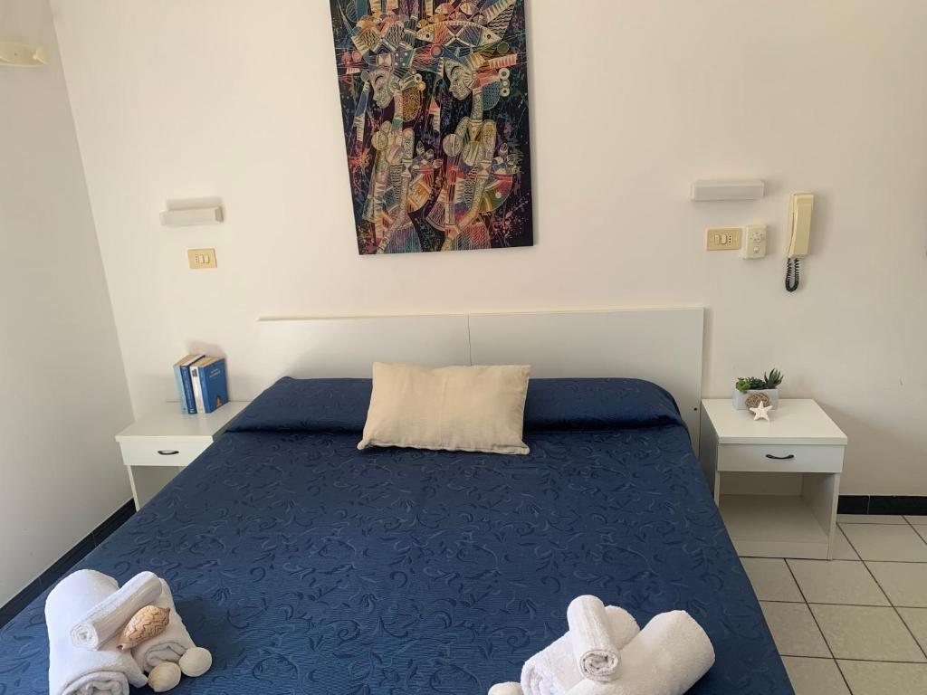 卡托利卡HOTEL LA PERGOLA的一间卧室配有蓝色的床和两张白色的桌子
