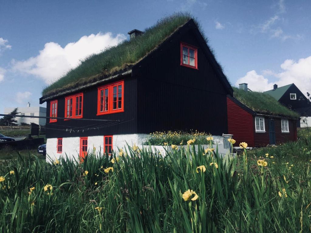 MiðvágurTurf House Cottage - Near Airport的黑白的草屋顶房子