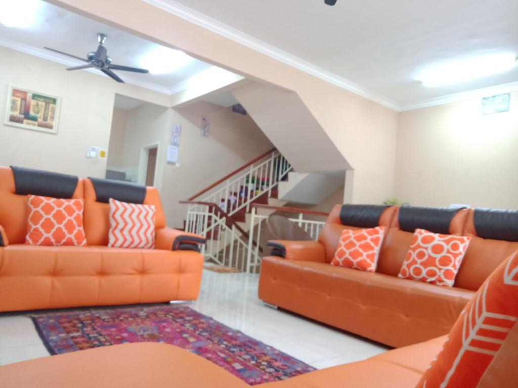 普崇Cosy P6 Homestay的客厅设有两张橙色沙发和楼梯