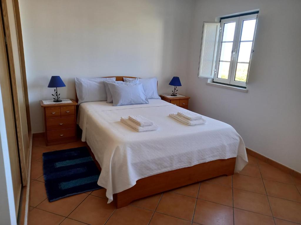 米尔芳提斯城T2,Casa Sol e Mar 50464/AL的一间卧室配有一张带2个床头柜的大型白色床