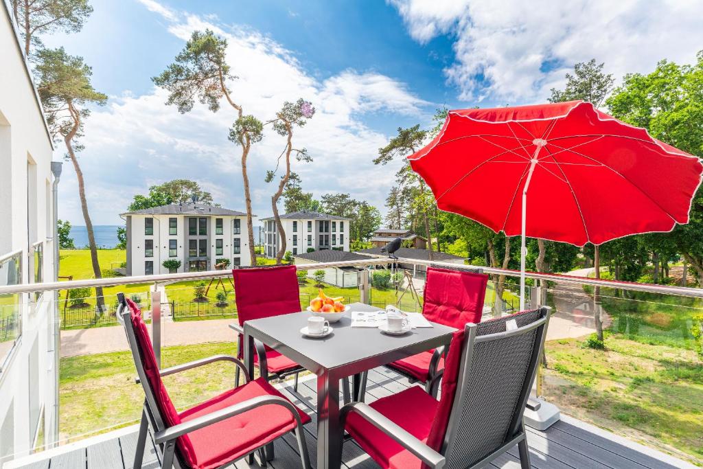 加兹尤瑟多姆Apartment "Marco Polo" - Haffresidenz的阳台配有带红伞的桌椅