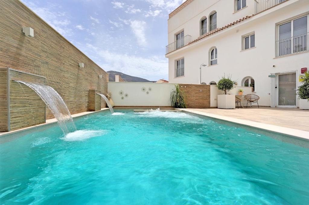 奥尔希瓦Alpujarra Secret的一座大楼前的游泳池,设有喷泉