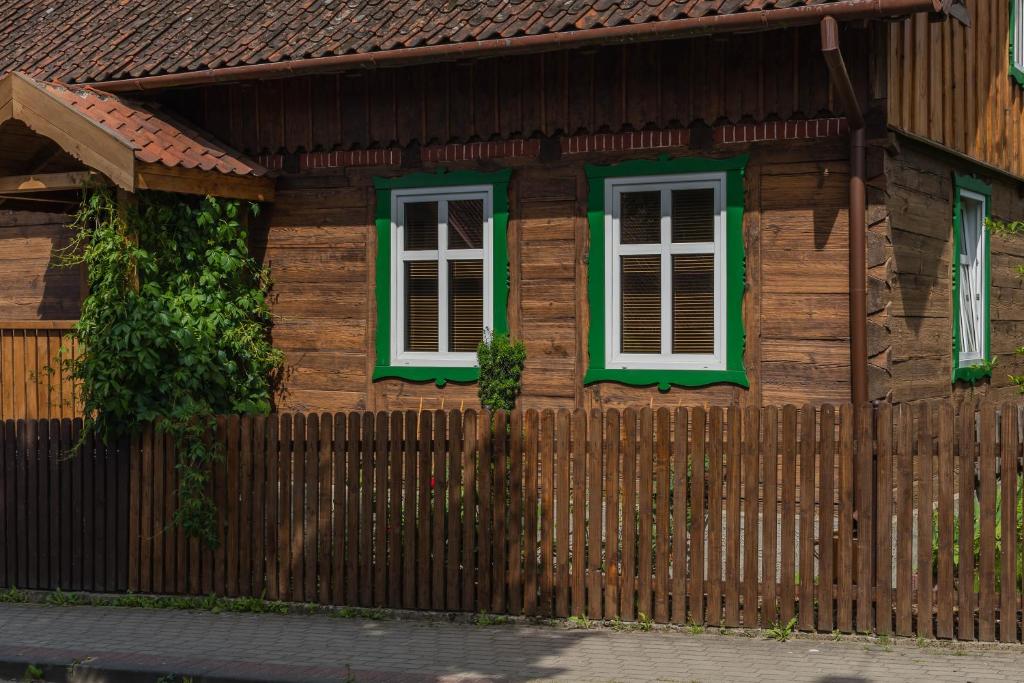 克鲁迪恩Dom w Krutyni的木屋设有绿色窗户和围栏
