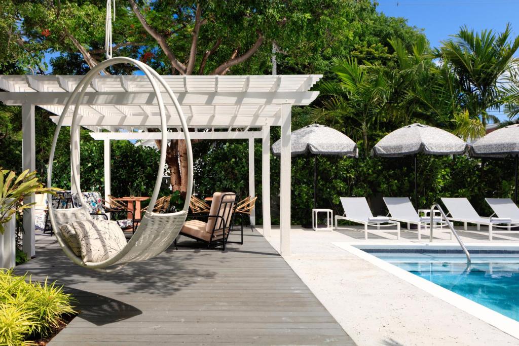 基韦斯特Ella's Cottages - Key West Historic Inns的游泳池旁设有椅子和秋千