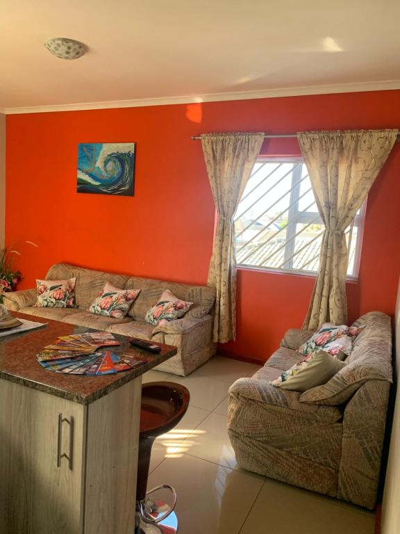 开普敦manu'z的客厅设有橙色墙壁、沙发和桌子