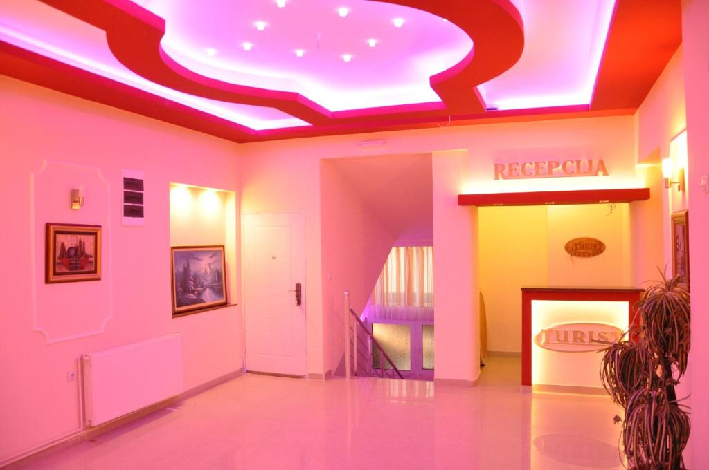 弗拉迪钦汉Rooms Turist的走廊设有粉红色和黄色的墙壁和 ⁇ 虹灯天花板