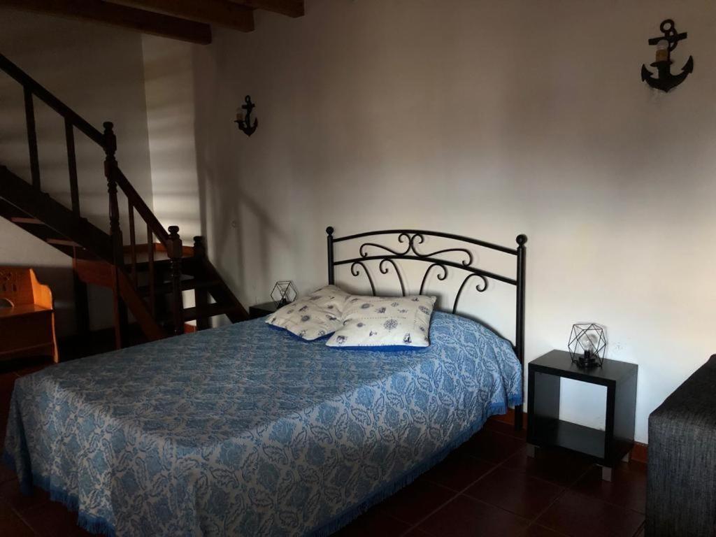 FeiteiraAdega do Golfinho的一间卧室配有一张带蓝色棉被的床和楼梯