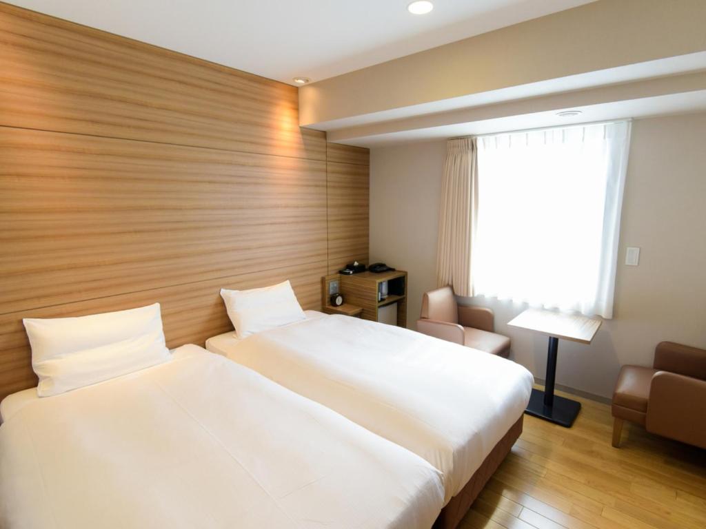 名古屋Via Inn Nagoya Shinkansen-guchi的酒店客房设有两张床和窗户。