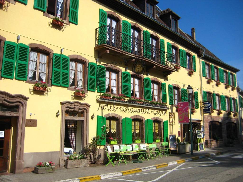 拉佩蒂特皮耶尔奥克斯多利斯玫瑰酒店及餐厅的绿色的黄色建筑,设有绿色百叶窗
