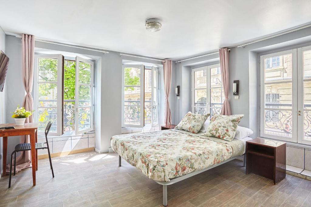 巴黎Le Petit Borda的卧室配有床、桌子和窗户。