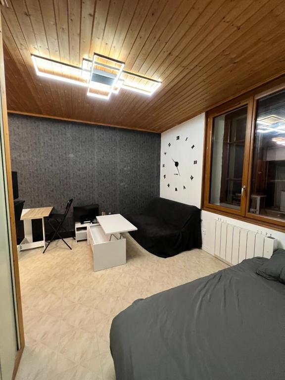 莱鲁斯Magnifique Studio de 20m2 pour 1 à 4 personnes的一间设有床、桌子和时钟的房间