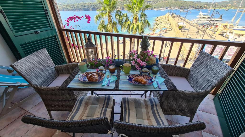 阿祖罗港La Pianotta Sulla Spiaggia的阳台上摆放着带食物和鲜花的桌子