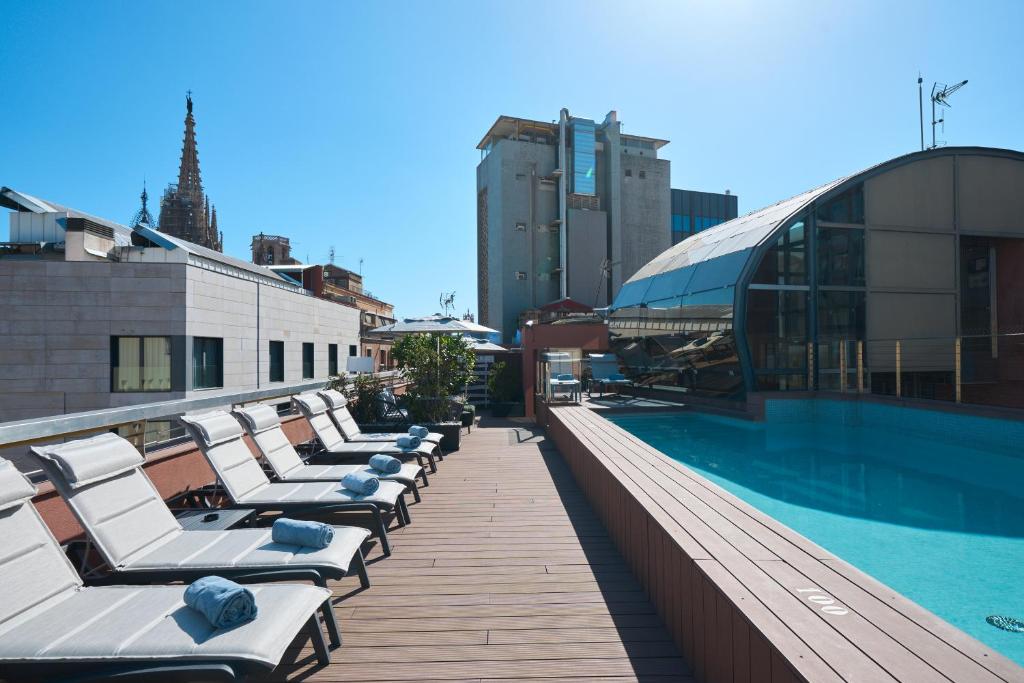 巴塞罗那卡泰多拉尔加泰罗尼亚酒店的屋顶游泳池上一排躺椅