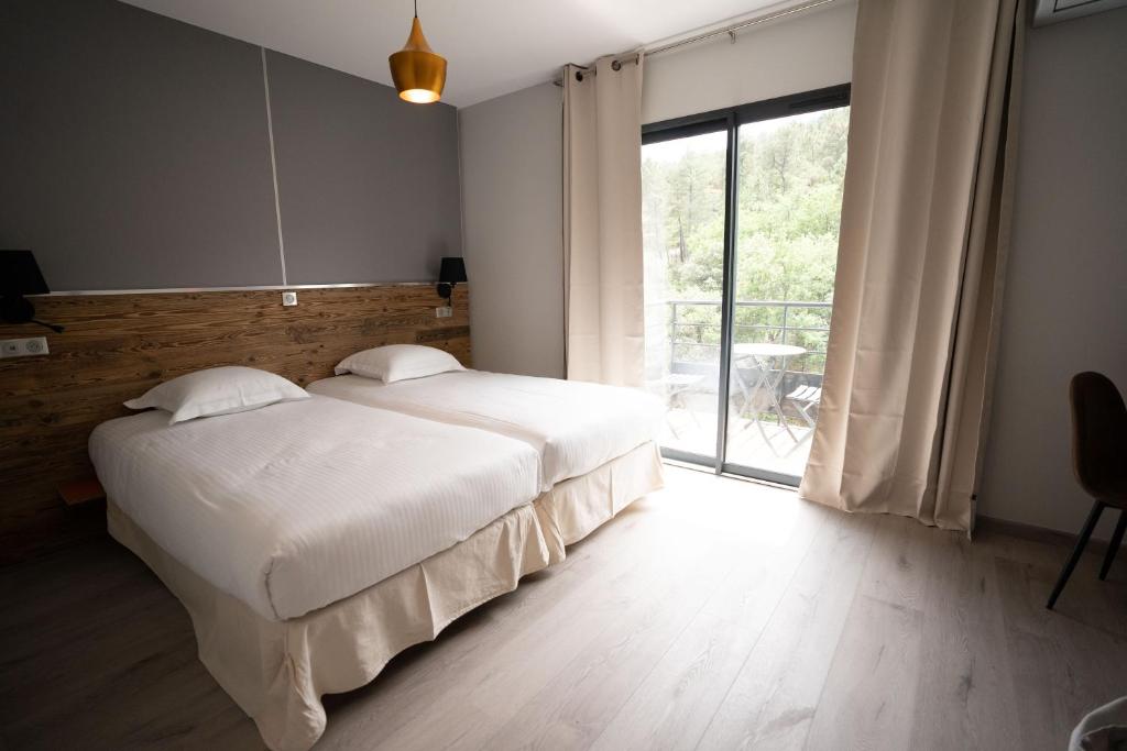 ChassiersHôtel Les Vignes的一间卧室设有一张大床和一个大窗户