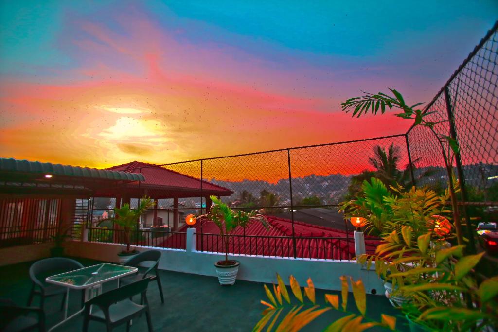 康提Kandyan Fo Rest的阳台配有桌椅,享有日落美景。