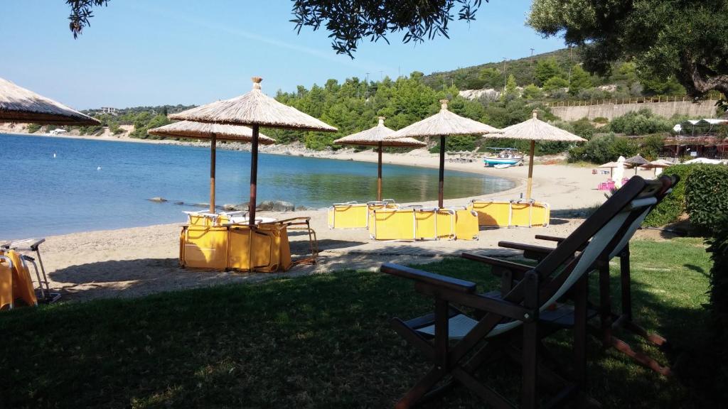 普萨克迪亚Porto Psakoudia的海滩上摆放着黄色的椅子和遮阳伞,水面上