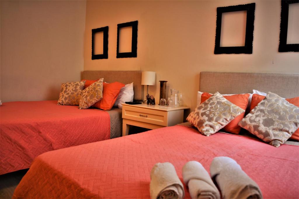 利马Kangaroo Wasi Airport Bed & Breakfast的宿舍间的两张床,配有红色床单和枕头