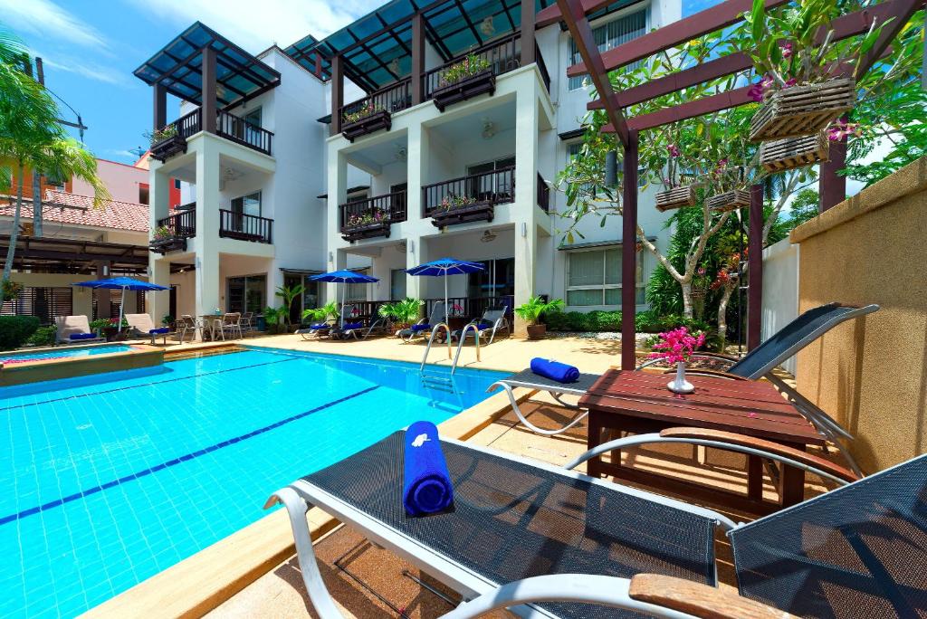 奥南海滩Krabi Apartment-SHA Extra Plus的一座带椅子和桌子的游泳池位于大楼旁