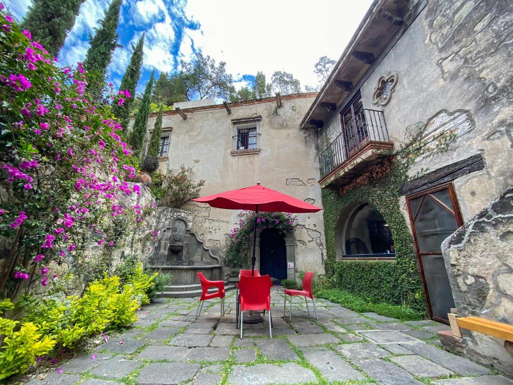 TotolacMolino de los Reyes By Rotamundos的大楼前的庭院配有红色椅子和遮阳伞