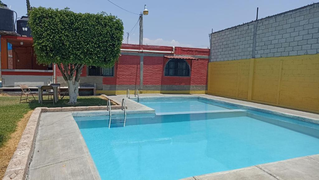 库奥特拉莫雷洛斯Casa De Descanso Cuautla Morelos的一座大型蓝色游泳池,位于大楼旁边