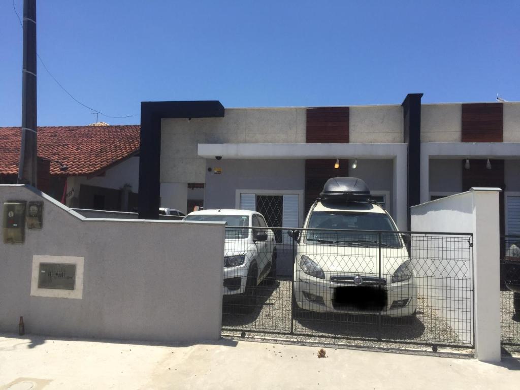 南圣弗朗西斯科Casa Enseada, Prainha, Praia Grande prox mar的两辆汽车停在房子前面的停车场