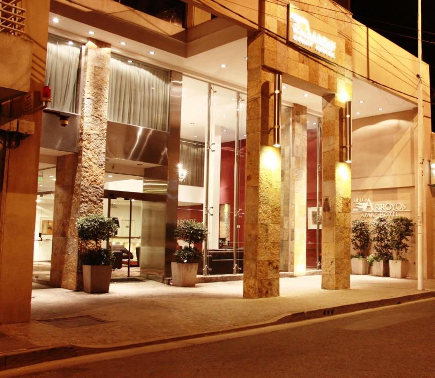 圣尼古拉斯De Los Arroyos Apart Hotel的一座在晚上在前面有盆栽植物的建筑