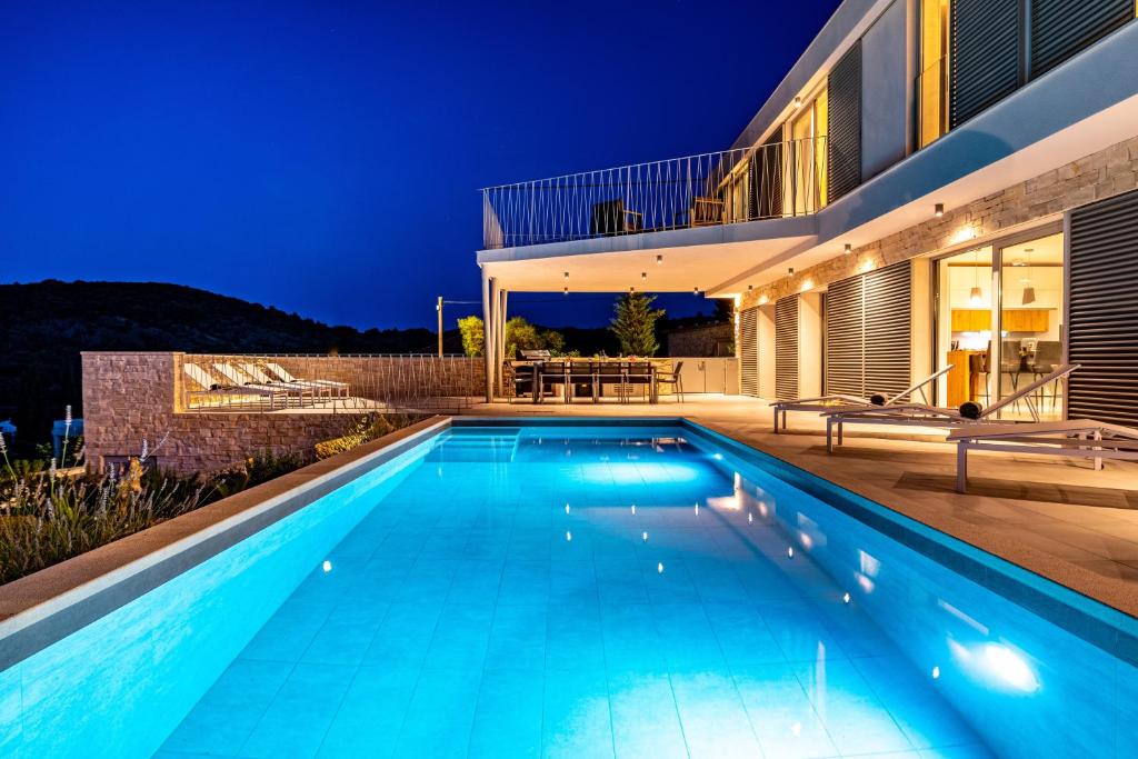 兹曼Villa Mezano Žman的夜间在房子前面的游泳池