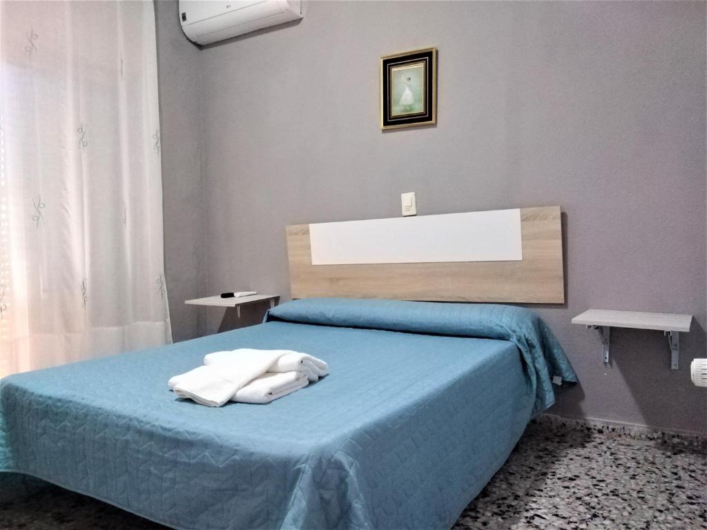 库列拉Habitaciones de Hostal a Primera linea de playa en Cullera的一间卧室配有蓝色的床和2条毛巾