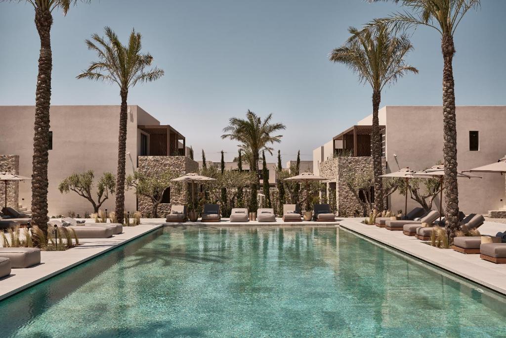科斯镇Theros All Suite Hotel - Adults Only的一个带棕榈树和躺椅的游泳池