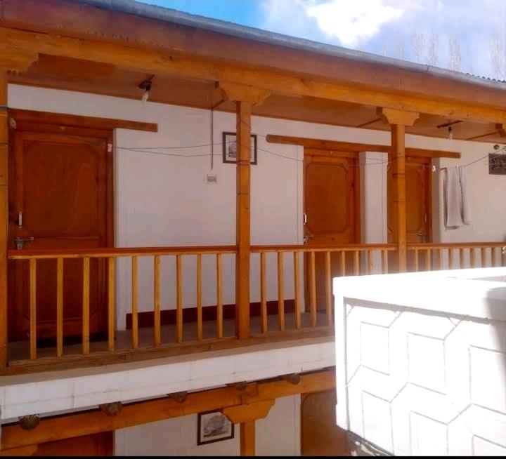 列城Gomang guest house Leh的一个带木柱的房屋的门廊和一个阳台