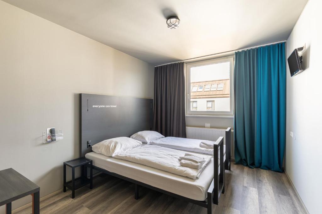 维也纳a&o维也纳中央火车站酒店的一间卧室配有一张带蓝色窗帘的床和一扇窗户